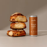 Stack of bread rolls next to a can of Protein Coffee on a neutral background