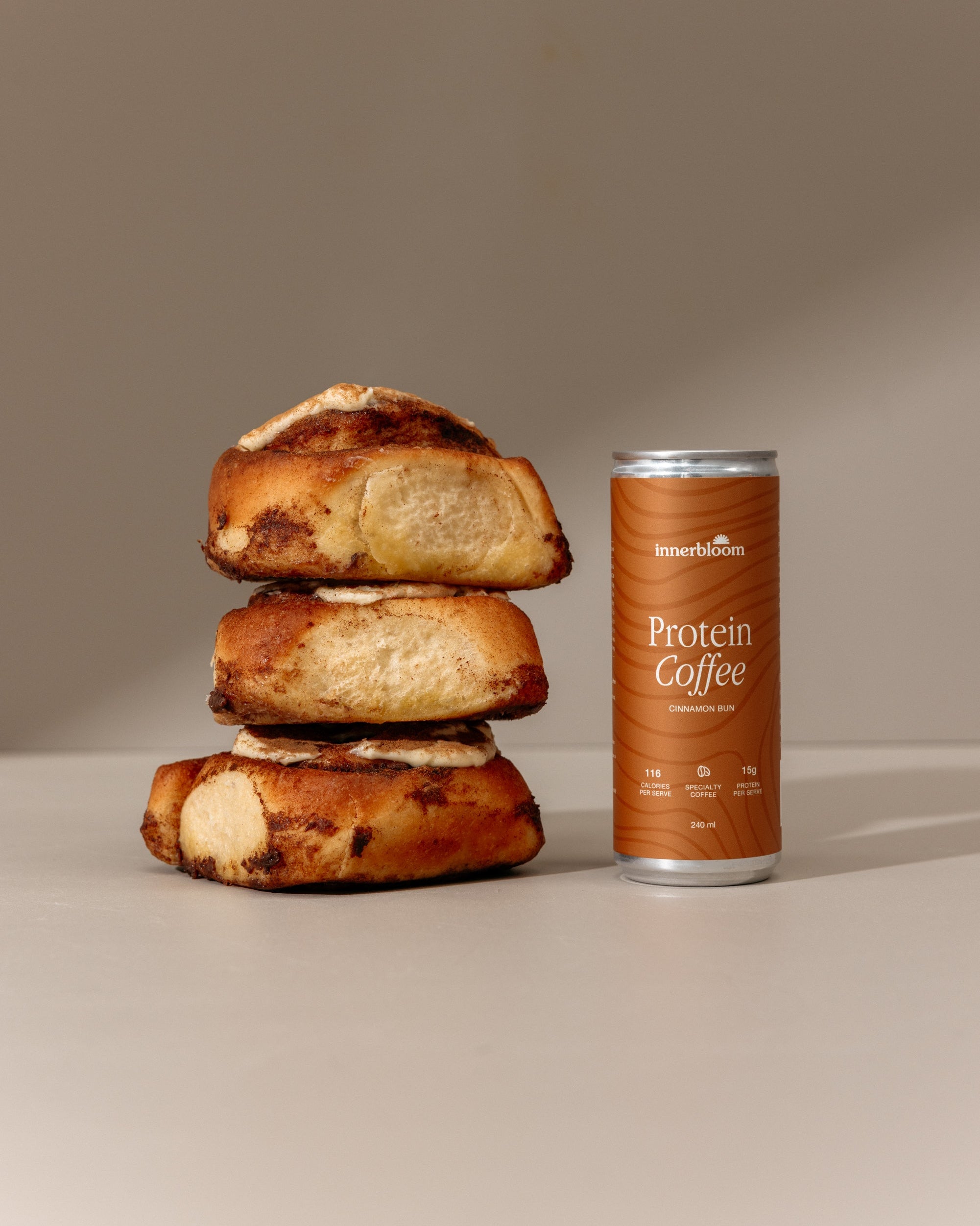 Stack of bread rolls next to a can of Protein Coffee on a neutral background